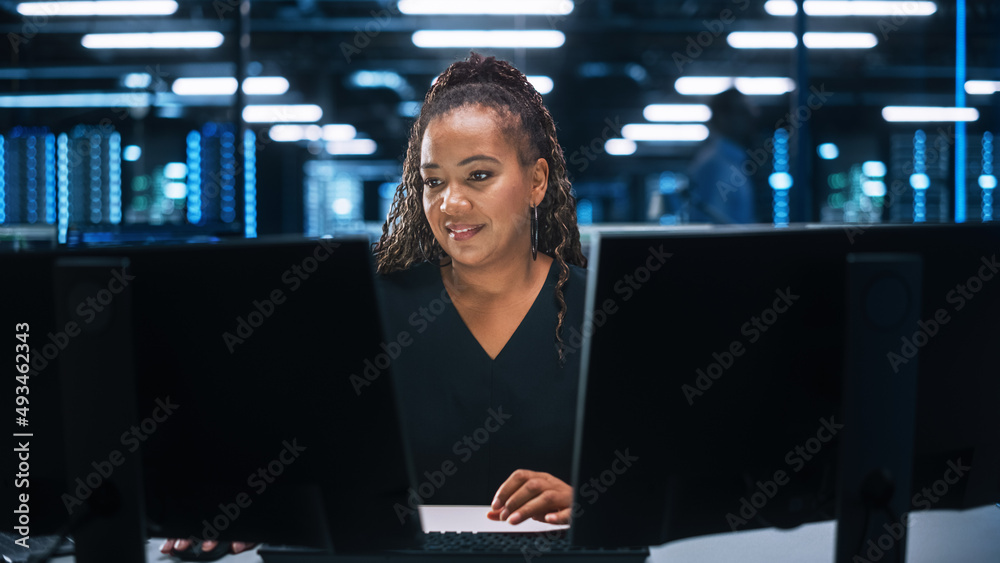 非裔美国女性IT专家在数据中心桌面工作的画像。系统管理员