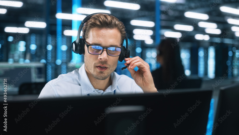 客户支持接线员在晚间办公室的电脑上进行耳机视频通话。呼叫中心代理，