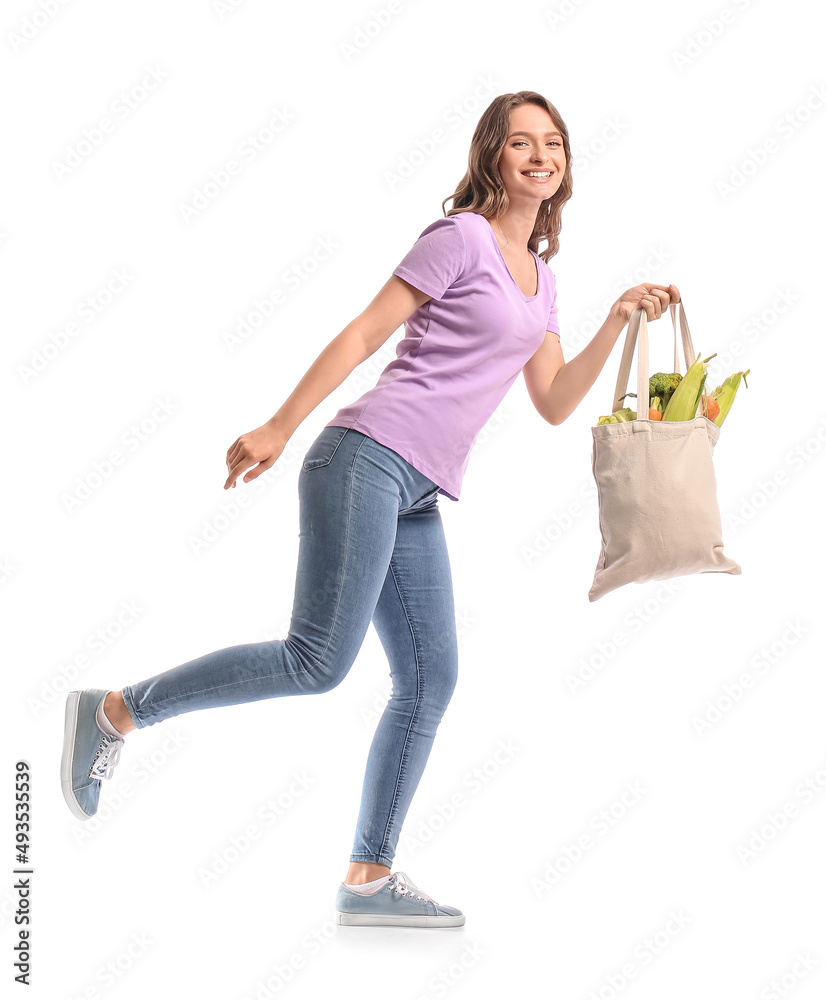 Young woman holding eco bag with healthy vegetables on white background