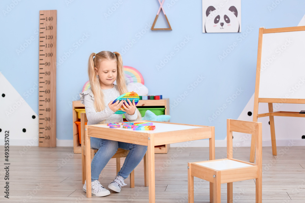 漂亮的小女孩坐在桌子旁，在儿童房里玩玩具