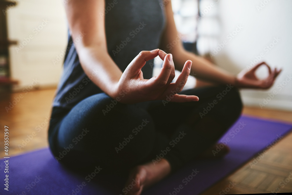 Finding my balance. Cropped shot of an unrecognizable woman sitting on a yoga mat and meditating alo