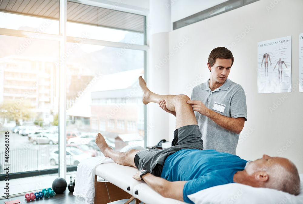 Gentle movements. Shot of a young male physiotherapist helping a client with leg exercises whos lyin