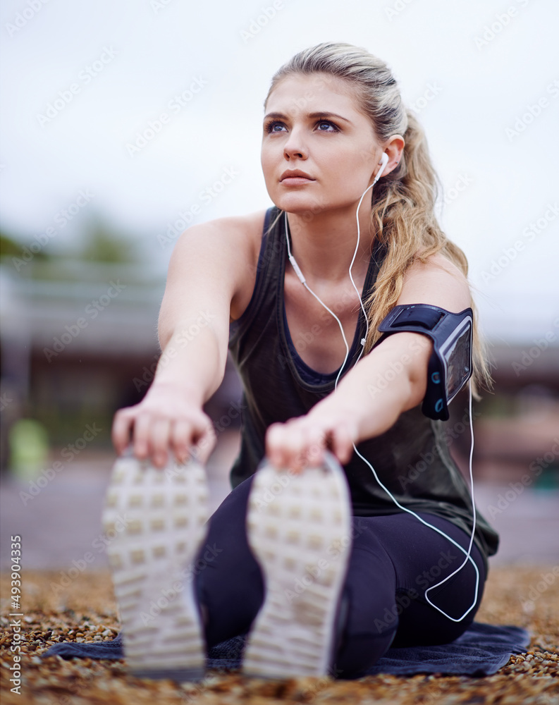 随着美妙的音乐进入区域。一名年轻女子在跑步前伸展双腿的镜头。