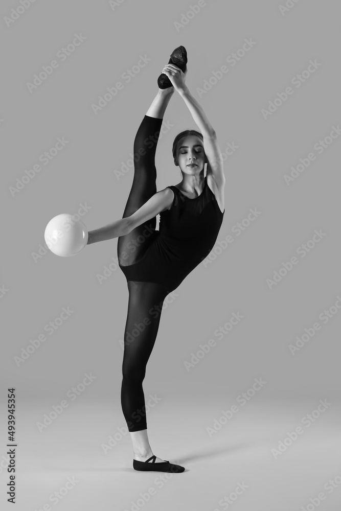 年轻漂亮女子持球做体操的灰度照片