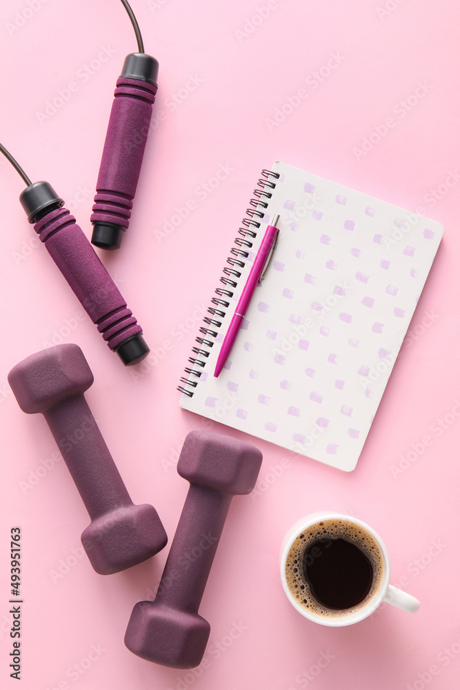 彩色背景的哑铃、跳绳、笔记本和一杯咖啡