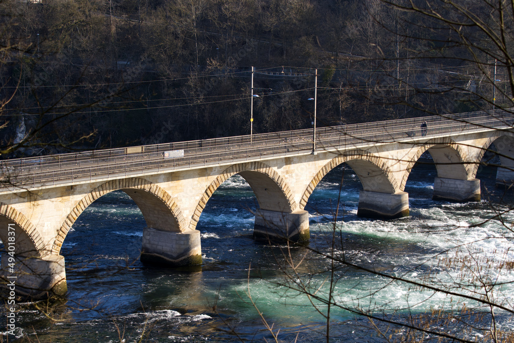 在阳光明媚的春日，俯瞰莱茵瀑布著名的铁路高架桥和岩石，关注背面