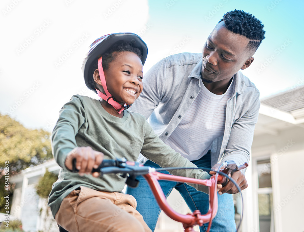 看着他。一个父亲教儿子在户外骑自行车的镜头。
