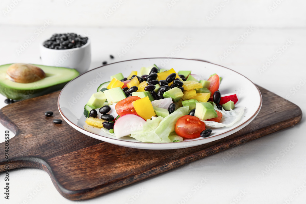 木板上放着一盘墨西哥蔬菜沙拉，放在浅色木桌上，特写