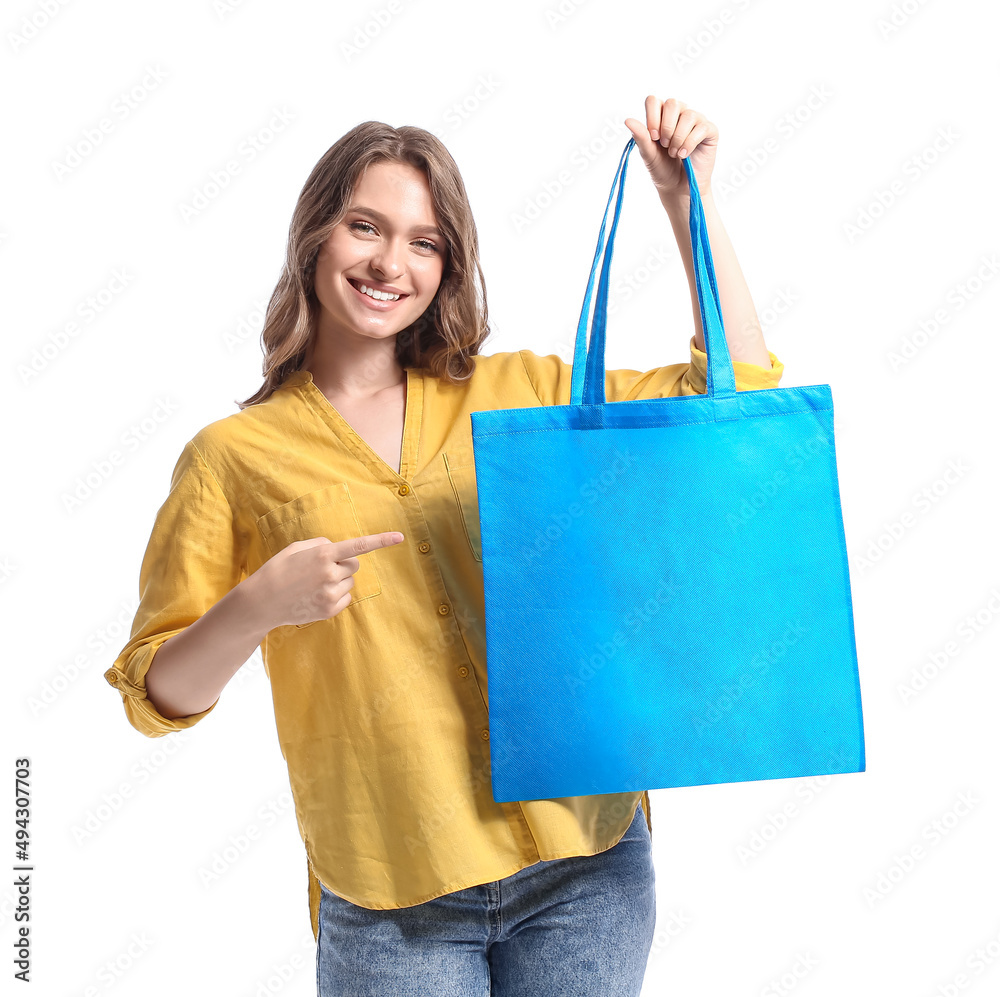 Pretty young woman pointing at blue eco bag on white background