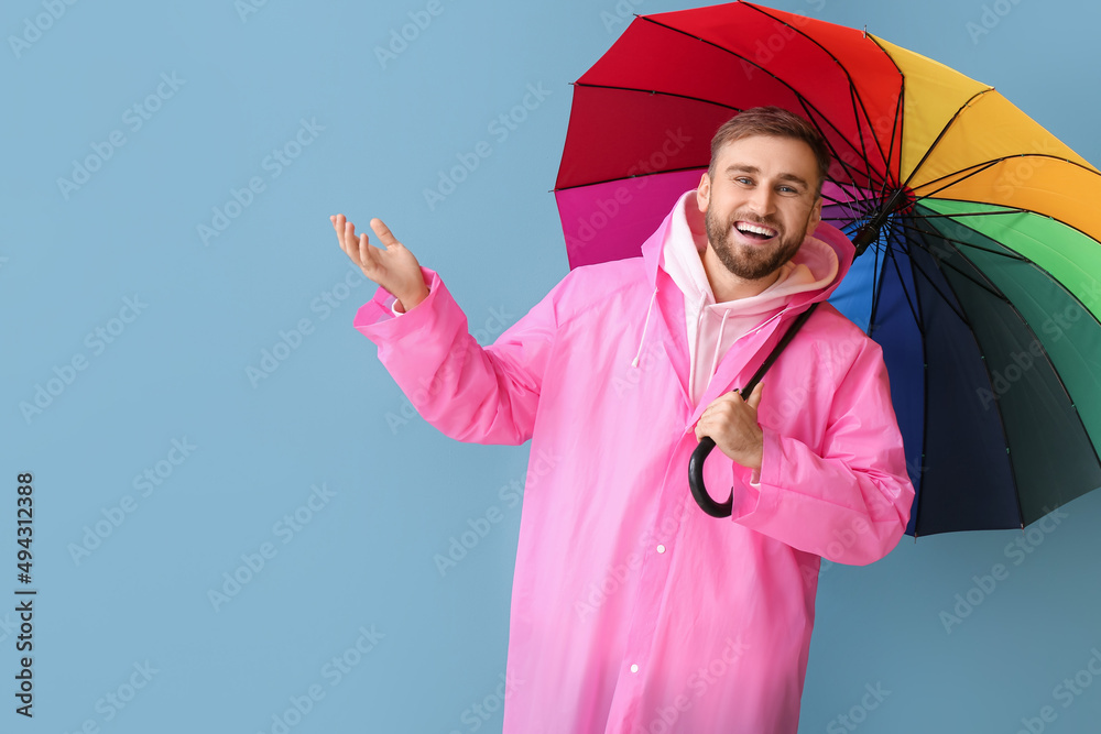 穿着时尚雨衣、打着雨伞的年轻人在彩色背景上展示了一些东西