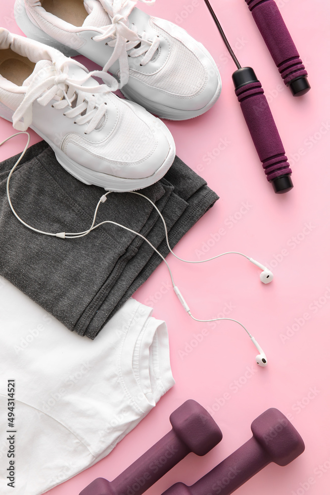 粉色背景的运动服、鞋子、耳机和设备，特写