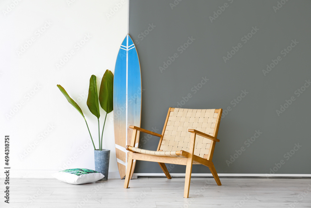 靠近墙壁的冲浪板、扶手椅和室内植物