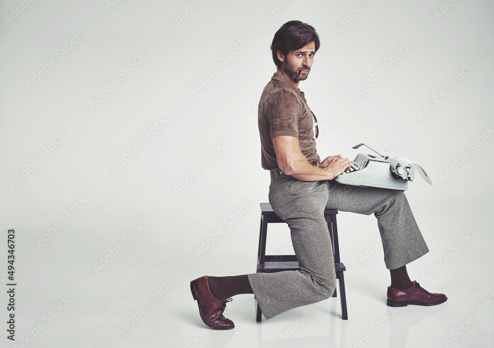 70年代时尚。一个70年代风格的商人坐在凳子上用打字机的工作室镜头。