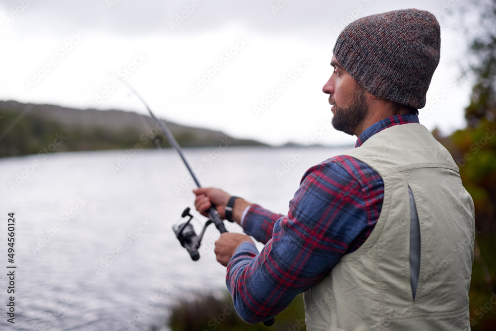 等着鱼咬。一个英俊的男人在天然湖中钓鱼的镜头。