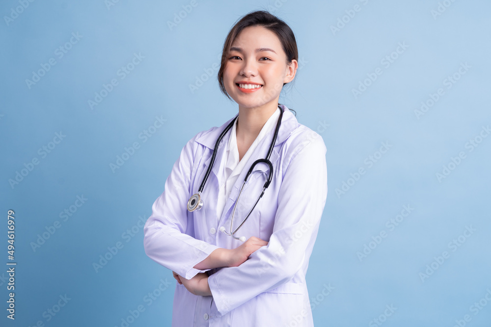 站在蓝色背景上的年轻亚洲女医生