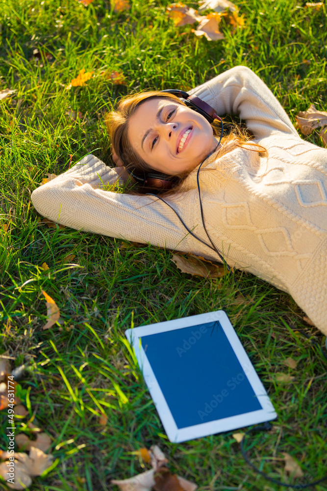 She loves her tunes. An attractive young woman listening to music on her digital tablet while outdoo