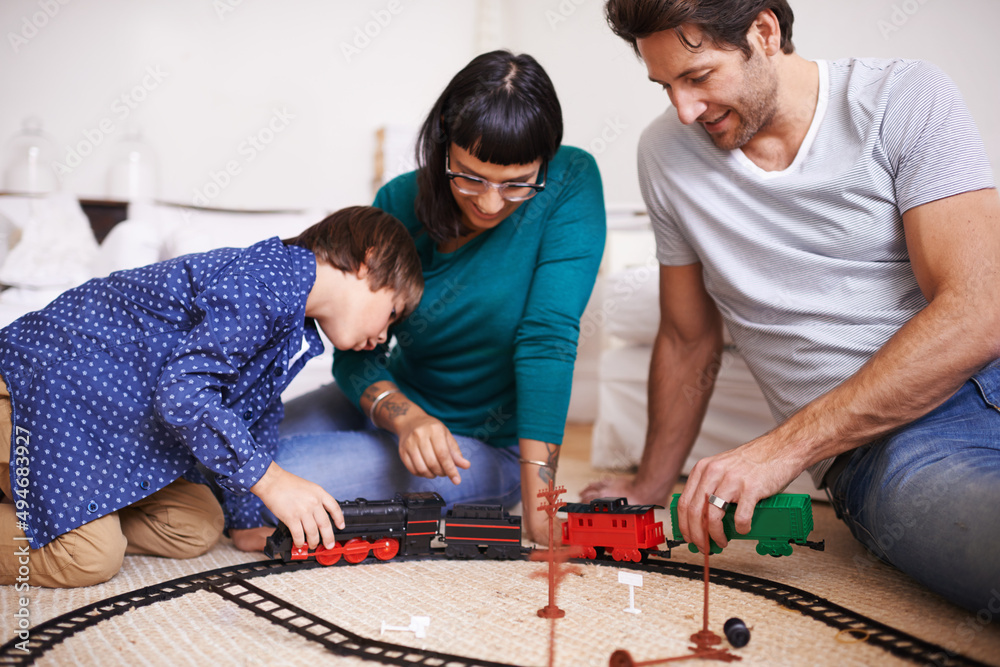 向他的父母展示如何搭火车。一个年轻家庭搭建玩具火车的镜头。