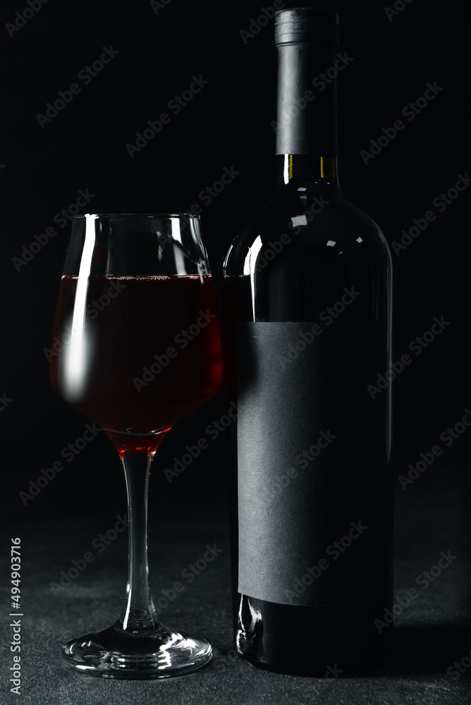 深色背景下的一杯又一瓶美味的红酒