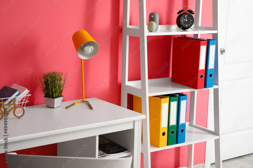 Modern workplace and shelf unit near color wall