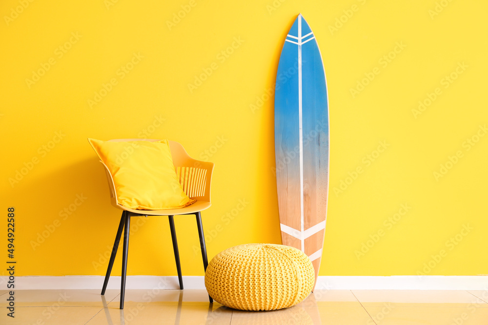 黄色墙壁附近的冲浪板、扶手椅和沙发