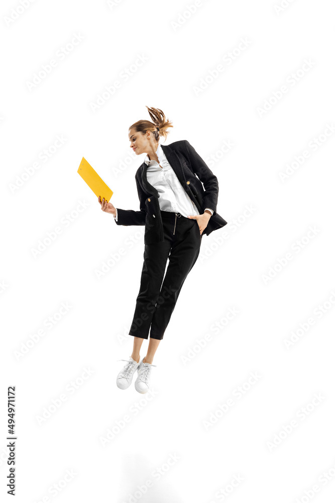 身穿黑色西装的年轻女商人在白色书房上用文件夹跳跃的动态肖像