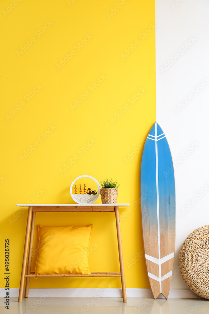 靠近彩色墙的冲浪板、桌子和柳条装饰