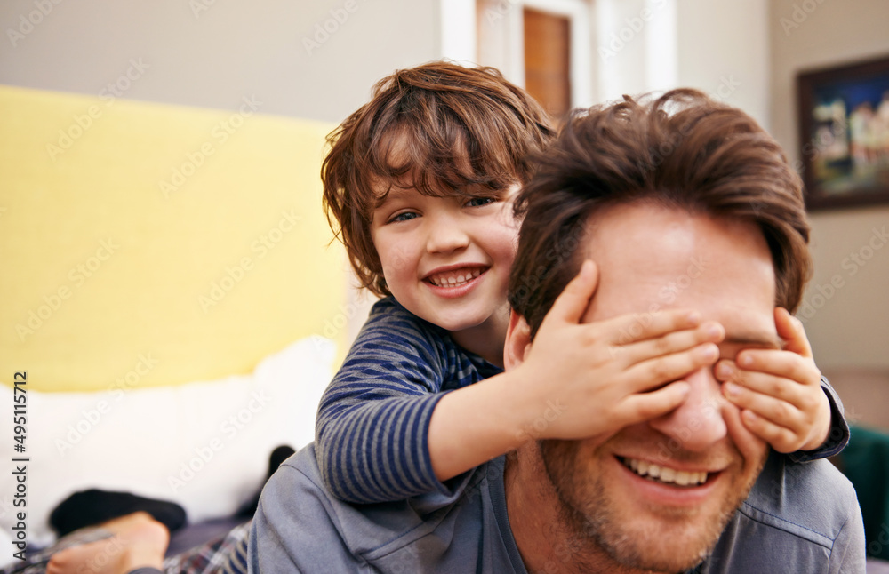 父亲和儿子玩得很开心。一个小男孩用手捂住父亲的眼睛的镜头。