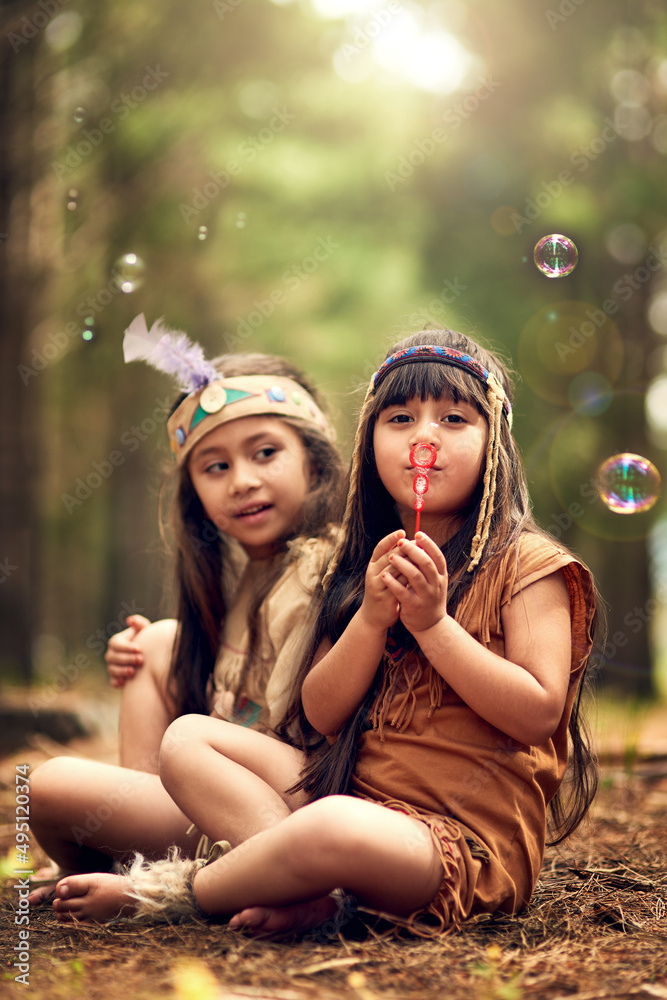 This is how we send smoke signals. Shot of two young kids blowing bubbles while playing dressup in t