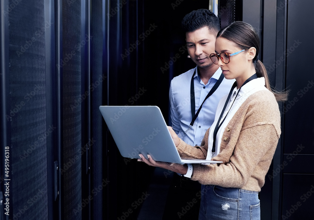 没有人像他们一样了解网络。两名技术人员在服务器机房一起工作的照片。