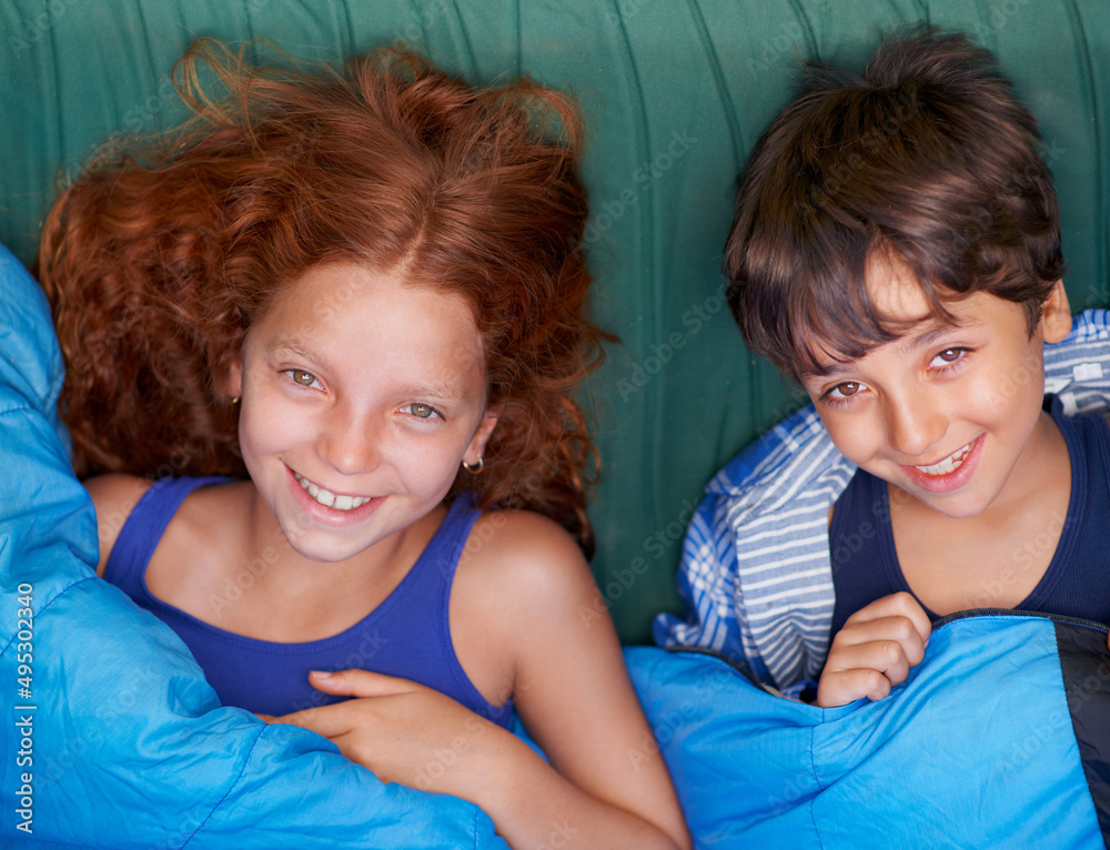 在帐篷里放松。一对年轻的兄弟姐妹躺着微笑的画像。