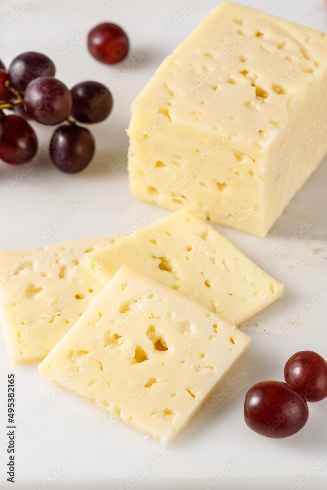 在厨房的大理石板上切一块芳香的奶酪和红葡萄。