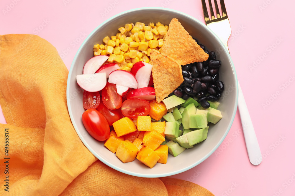 一碗墨西哥蔬菜沙拉，粉色背景下有黑豆、萝卜和玉米片，特写
