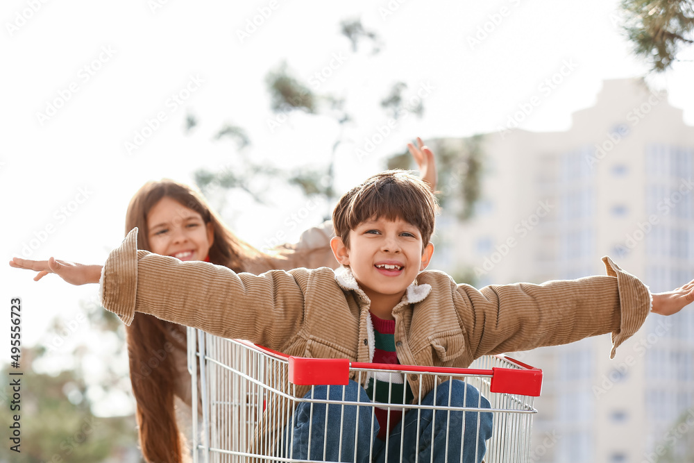 可爱的孩子在户外玩购物车
