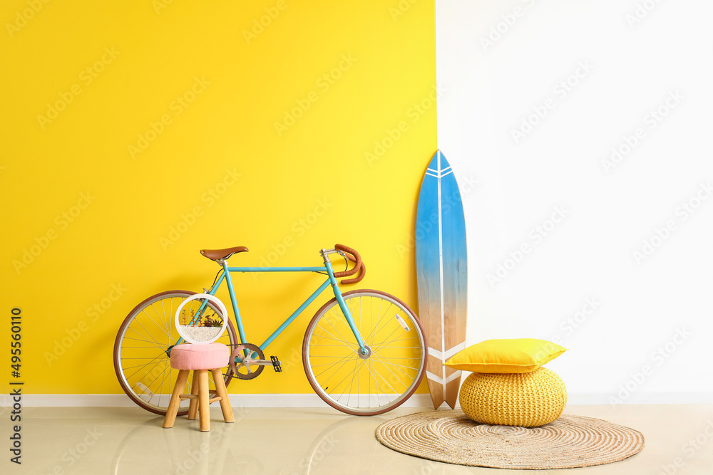 靠近彩色墙的冲浪板、自行车、桌子和沙发