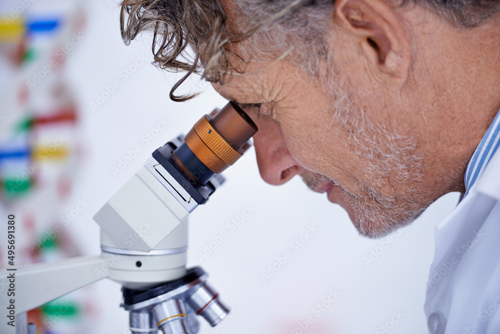 我们这里有什么……一张成熟科学家在实验室使用显微镜的裁剪照片。