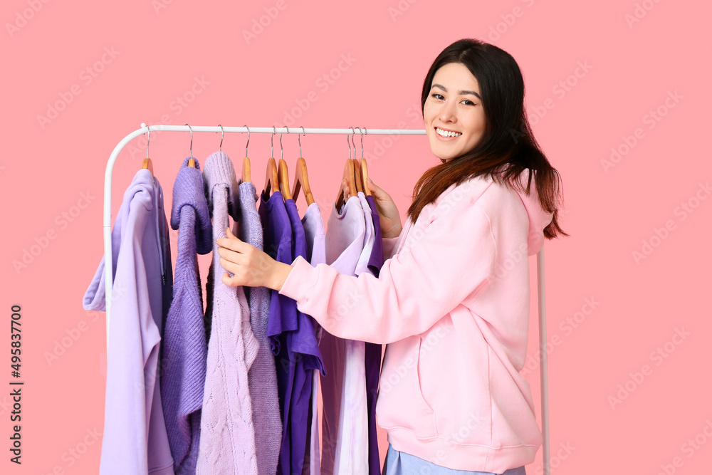 年轻的亚洲女性和粉色背景紫色衣服的架子