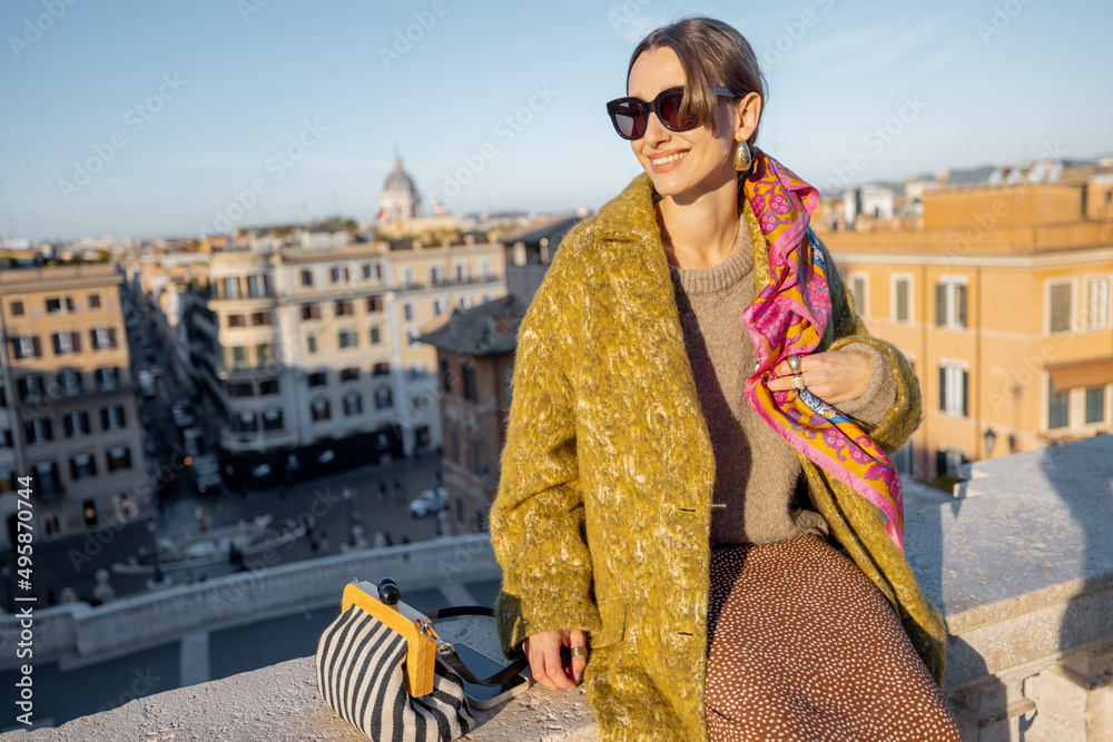 一个女人坐在著名的西班牙台阶上，欣赏着罗马美丽的早晨城市景观。老