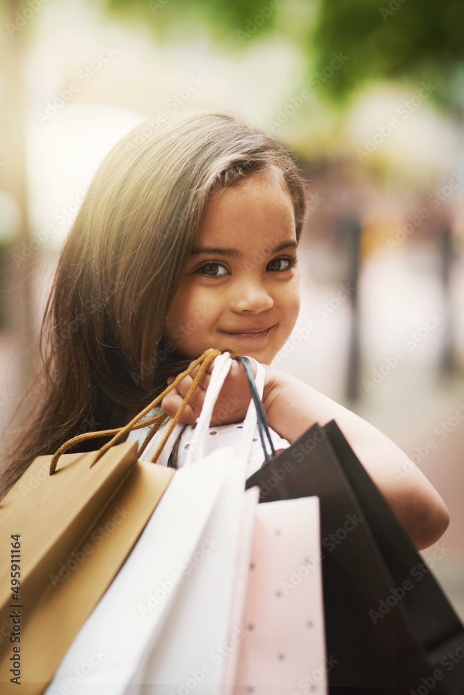 我不知道购物会这么有趣。一个可爱的小女孩拿着购物袋的画像