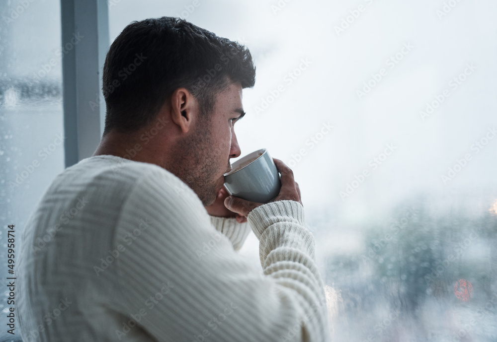 A simple break will bring you back to you. Shot of a young man having coffee and looking out of a wi