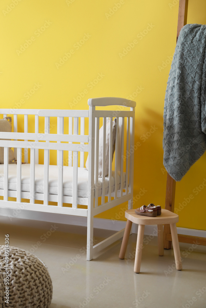 现代儿童房，靠近彩色墙，配有舒适的婴儿床