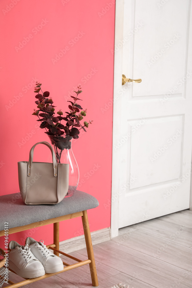 带袋子的软长椅，花瓶里的桉树和粉色墙壁附近的女性运动鞋