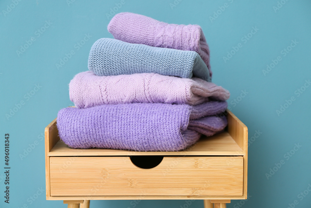 彩色墙附近桌子上的一堆时尚毛衣