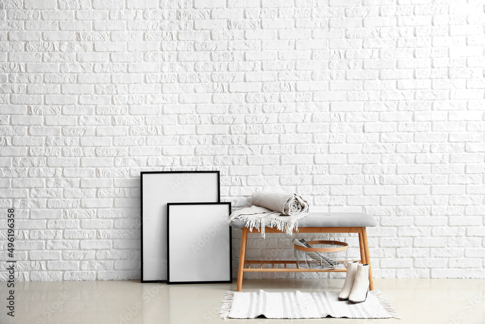 白色砖墙附近的带格子、篮子、鞋子和空白框架的软长椅