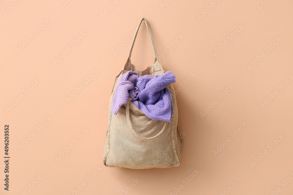 彩色墙上挂着淡紫色毛衣的袋子