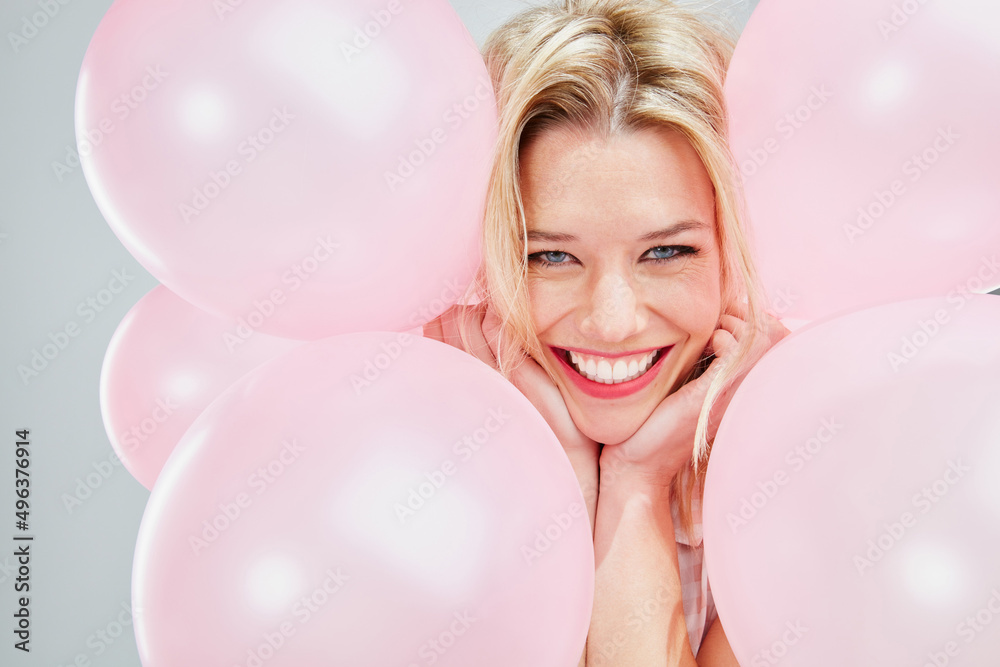 我不知道为什么，但我很高兴。一个漂亮的年轻女人拿着粉色气球摆姿势的裁剪镜头。