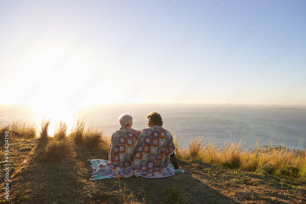 分享甜蜜时刻。一对高级夫妇一起坐在山坡上的画面。