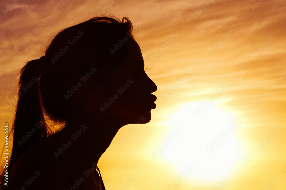 一个女人在美丽的天空下亲吻太阳的特写。一个女人亲吻太阳的侧视