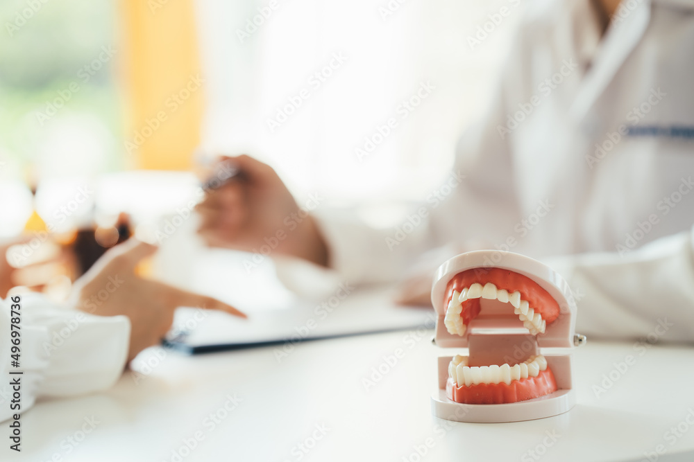 特写牙医手持牙齿模型义齿和探照镜工具，用于向其展示和解释
