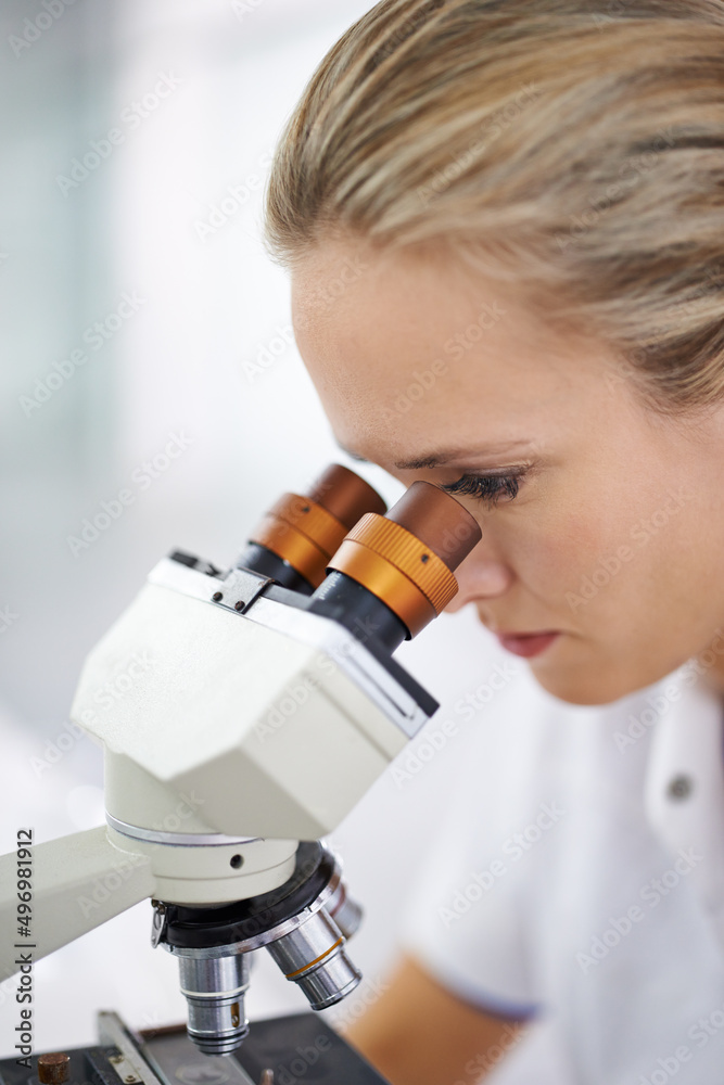 展望科学的未来。一位美女在实验室用显微镜工作的照片