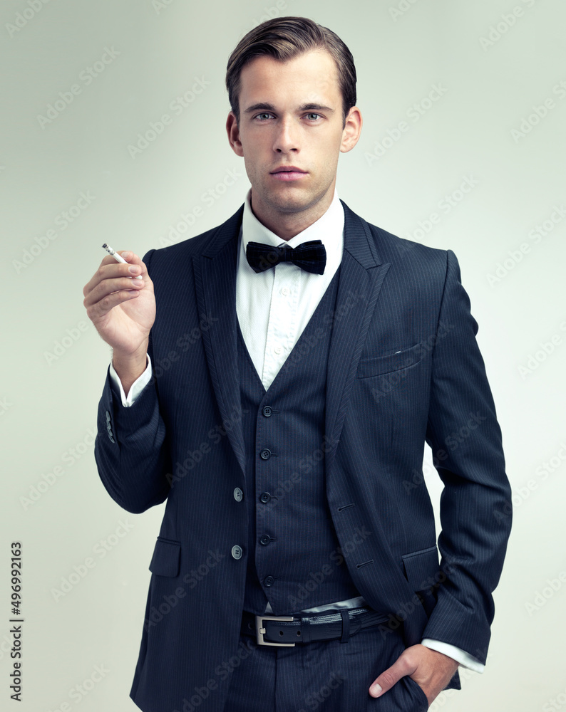 Suave and sophisticated. A studio portrait of a confident young gentleman smoking a cigarette.